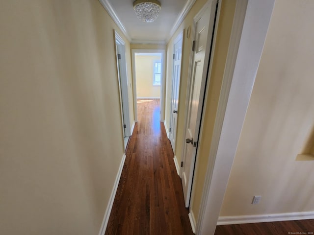 hall featuring crown molding, dark wood finished floors, baseboards, and a notable chandelier