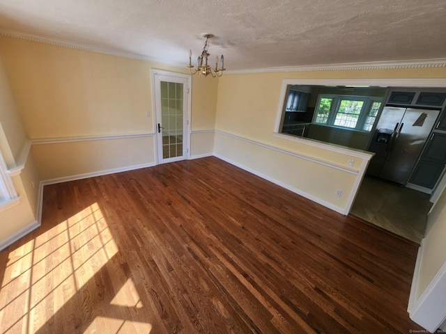 unfurnished dining area featuring crown molding, a textured ceiling, wood finished floors, and a notable chandelier