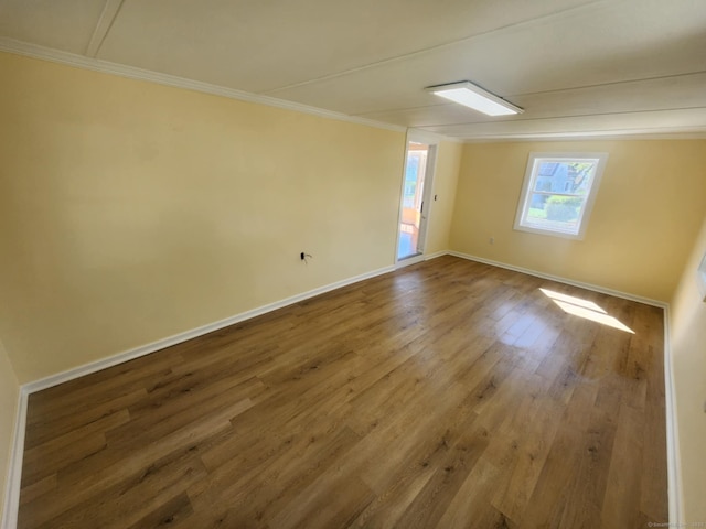 spare room with baseboards, ornamental molding, and wood finished floors