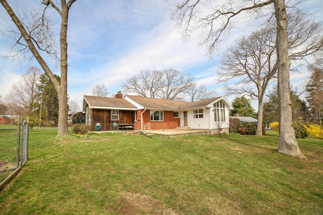 rear view of house with a chimney, fence, and a yard