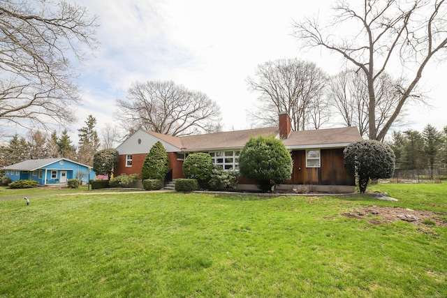 ranch-style home featuring a chimney and a front lawn