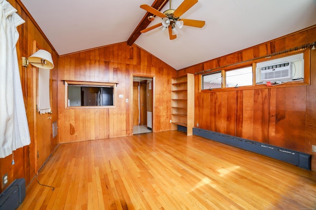 unfurnished living room with ceiling fan, a wall mounted AC, a baseboard heating unit, wood finished floors, and wooden walls
