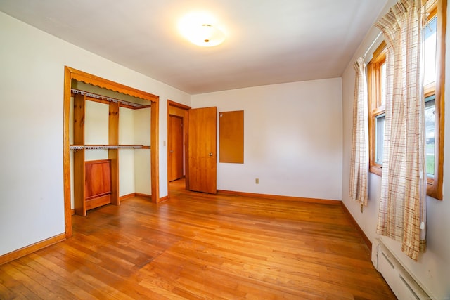 unfurnished bedroom featuring baseboards, light wood finished floors, and baseboard heating