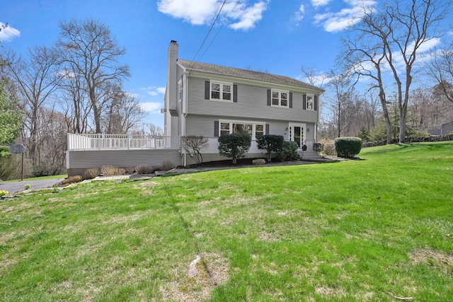 view of front of home featuring a front yard, a wooden deck, and a chimney