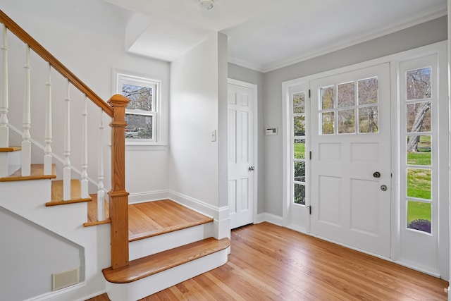 entrance foyer with visible vents, baseboards, ornamental molding, light wood-type flooring, and stairway