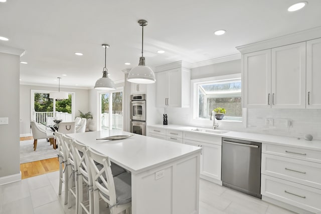 kitchen with a sink, ornamental molding, appliances with stainless steel finishes, and recessed lighting