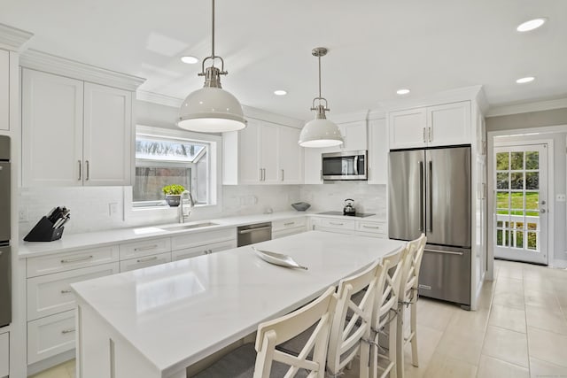 kitchen with crown molding, recessed lighting, a center island, appliances with stainless steel finishes, and a sink
