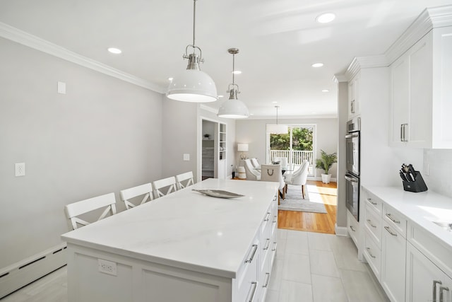 kitchen with white cabinets, recessed lighting, a center island, a baseboard heating unit, and stainless steel double oven