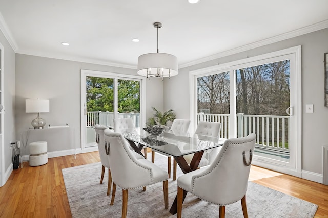 dining area with light wood-style floors, an inviting chandelier, baseboards, and ornamental molding