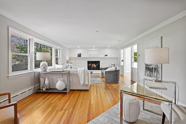 living room featuring light wood finished floors, a baseboard radiator, ornamental molding, and a warm lit fireplace