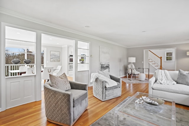 living area featuring stairway, light wood-style floors, and ornamental molding