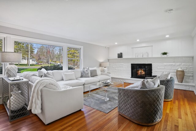 living area with a stone fireplace, recessed lighting, and wood finished floors
