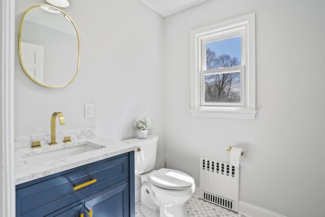half bathroom featuring radiator heating unit, vanity, baseboards, and toilet