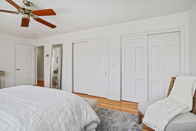 bedroom featuring ceiling fan, two closets, wood finished floors, and baseboards