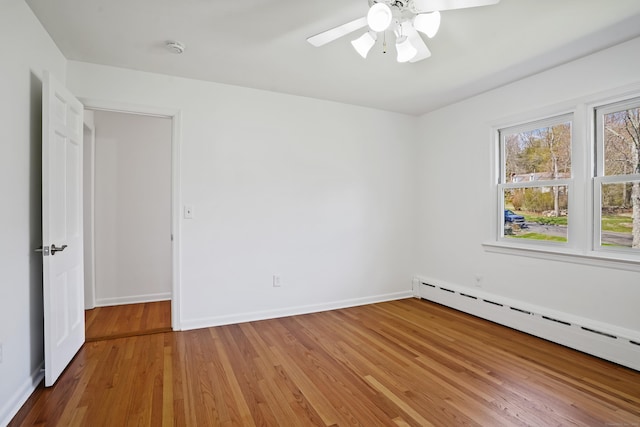 unfurnished room featuring light wood-type flooring, a baseboard heating unit, baseboards, and a ceiling fan
