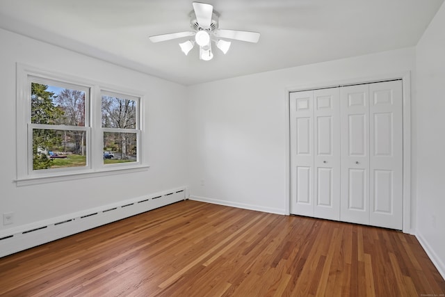 unfurnished bedroom with a closet, baseboards, a baseboard radiator, light wood-type flooring, and ceiling fan
