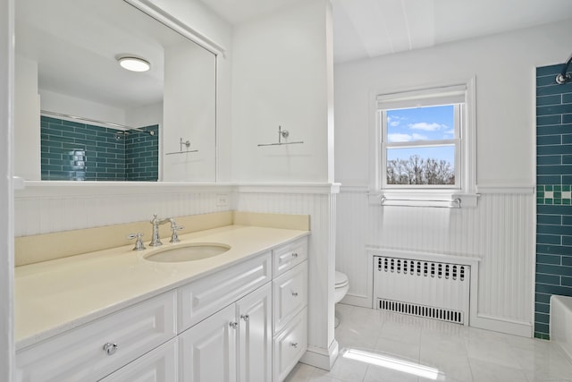 bathroom with radiator heating unit, tiled shower, wainscoting, and toilet