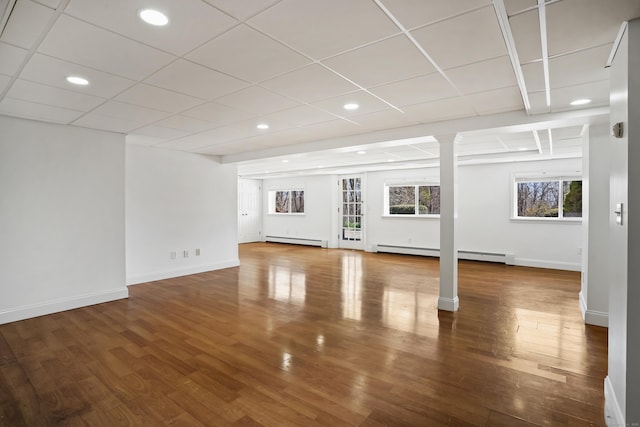 unfurnished living room with a baseboard radiator, wood finished floors, a baseboard heating unit, and baseboards
