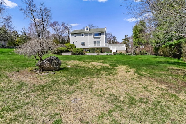 rear view of house featuring a yard, a deck, and stairs