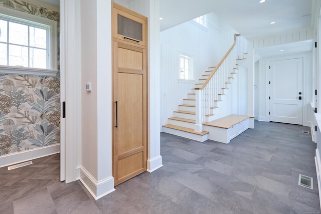 entryway with stairs, baseboards, wallpapered walls, and visible vents