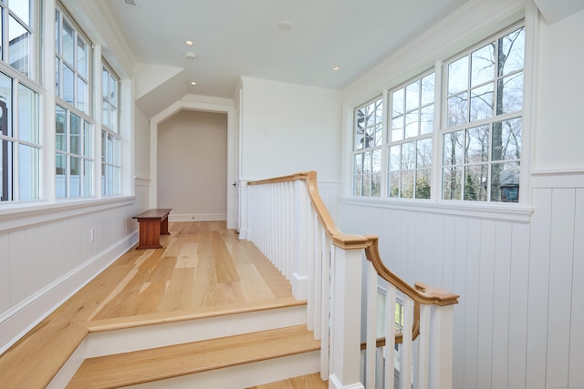stairway with wood finished floors, wainscoting, and recessed lighting