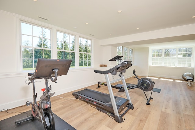 exercise room with light wood finished floors, visible vents, and plenty of natural light
