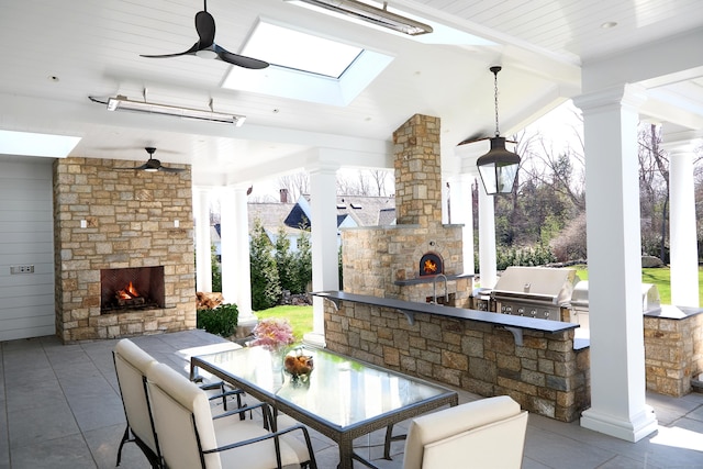 view of patio / terrace with outdoor dining space, an outdoor kitchen, ceiling fan, grilling area, and an outdoor stone fireplace