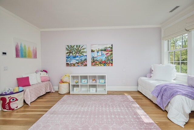 bedroom featuring visible vents, wood finished floors, baseboards, and ornamental molding