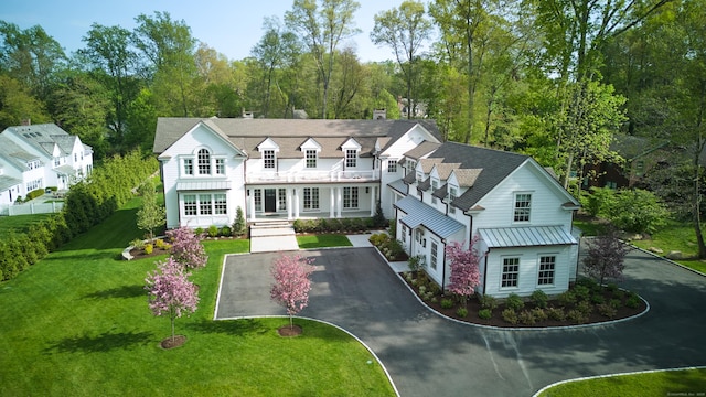 view of front of house with metal roof, a front lawn, a standing seam roof, and driveway