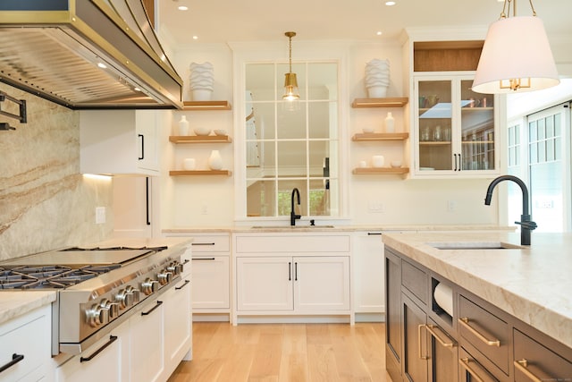 kitchen featuring a sink, wall chimney range hood, ornamental molding, open shelves, and stainless steel gas stovetop