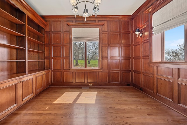 14 Turnberry Rd, Wallingford, CT 06492 - unfurnished room featuring a chandelier, plenty of natural light, light wood-style floors, and wooden walls