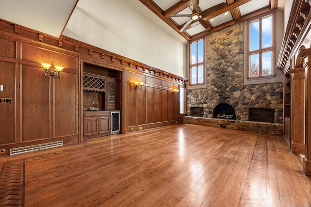 14 Turnberry Rd, Wallingford, CT 06492 - unfurnished living room with beverage cooler, a stone fireplace, hardwood / wood-style floors, beamed ceiling, and a high ceiling