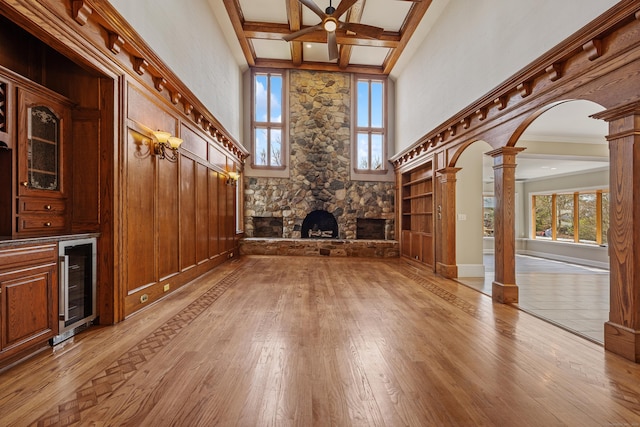 14 Turnberry Rd, Wallingford, CT 06492 - unfurnished living room featuring beverage cooler, ornate columns, a fireplace, light wood-type flooring, and a high ceiling