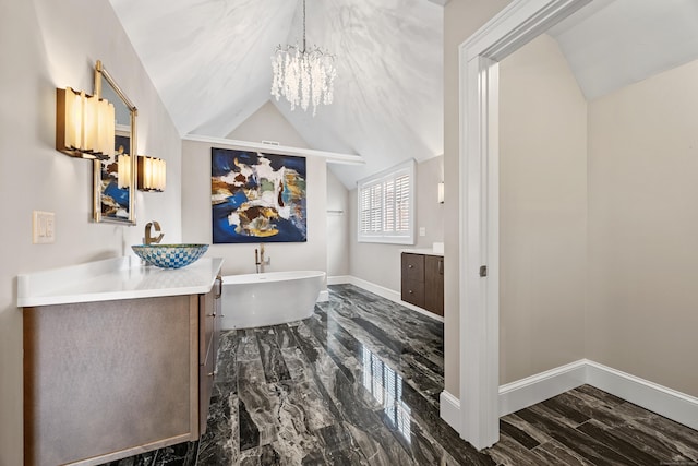 full bathroom with a freestanding tub, vanity, baseboards, and lofted ceiling