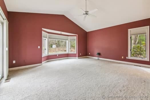 spare room with baseboards, a ceiling fan, vaulted ceiling, and carpet flooring