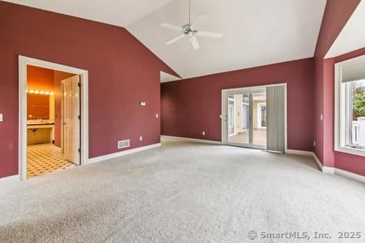 interior space with carpet floors, ceiling fan, lofted ceiling, and visible vents
