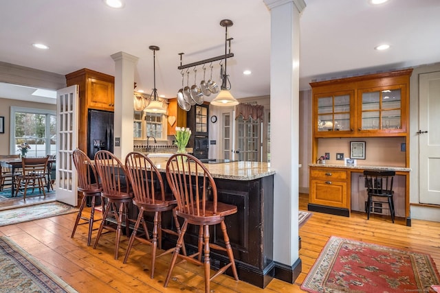 120 Boston Post Rd, Old Lyme, CT 06371 - kitchen with brown cabinets, light wood-style flooring, light stone counters, glass insert cabinets, and recessed lighting