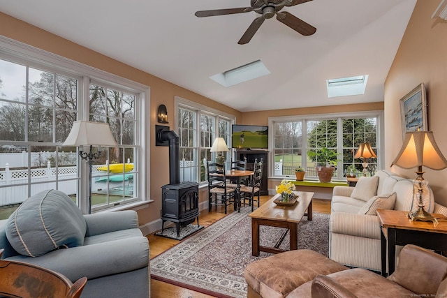 120 Boston Post Rd, Old Lyme, CT 06371 - living room featuring a skylight, a wood stove, a ceiling fan, wood finished floors, and vaulted ceiling