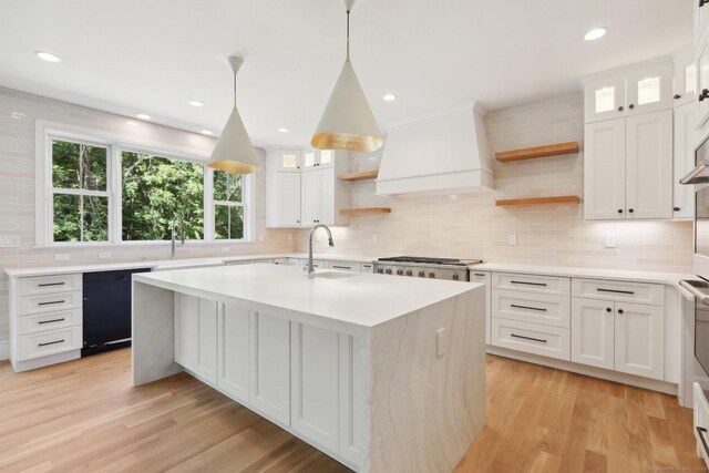 kitchen with open shelves, dishwasher, light countertops, a sink, and premium range hood
