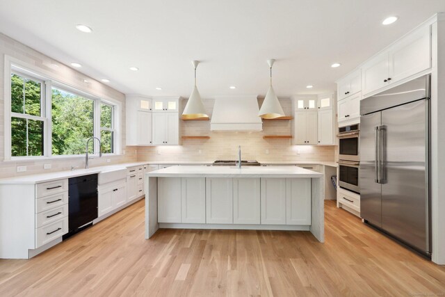kitchen featuring stainless steel appliances, premium range hood, light countertops, and white cabinetry