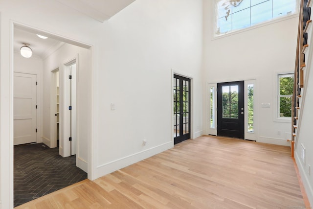 foyer with light wood-type flooring, a wealth of natural light, stairway, and baseboards