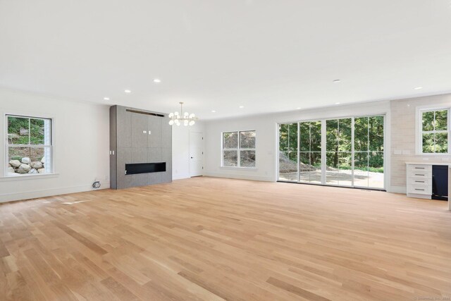 unfurnished living room featuring a chandelier, light wood-type flooring, a healthy amount of sunlight, and recessed lighting