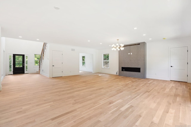 unfurnished living room featuring a chandelier, recessed lighting, light wood-style flooring, and baseboards