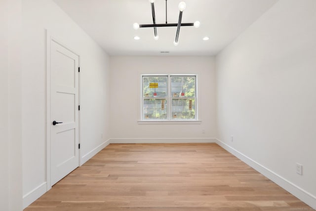 unfurnished room with light wood-style floors, recessed lighting, a notable chandelier, and baseboards
