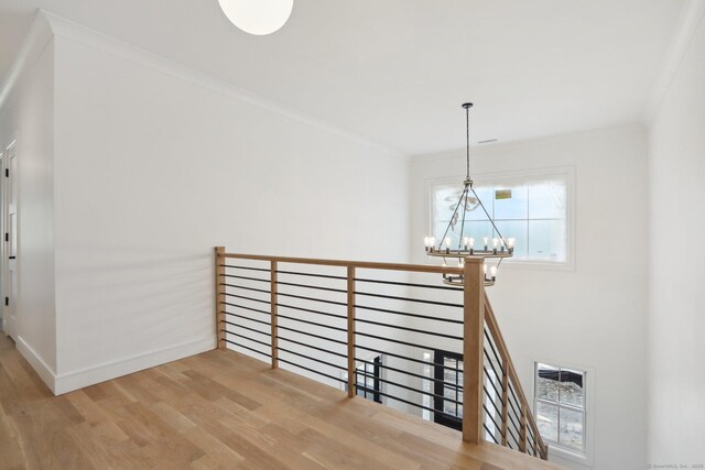 stairway featuring crown molding, baseboards, a chandelier, and wood finished floors