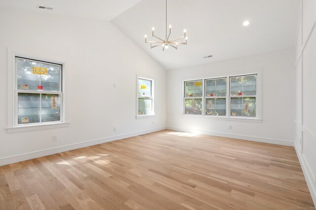 empty room featuring light wood-style flooring, high vaulted ceiling, an inviting chandelier, and visible vents