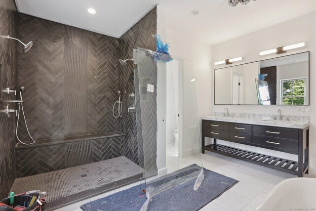 full bath with a shower stall, toilet, marble finish floor, a sink, and double vanity