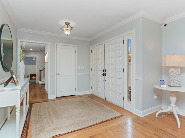 foyer entrance featuring baseboard heating, baseboards, ornamental molding, and wood finished floors
