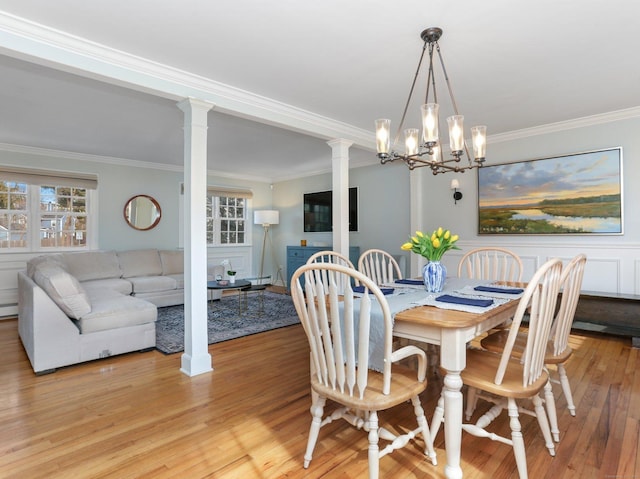 dining space with crown molding, ornate columns, a baseboard radiator, light wood-style flooring, and a notable chandelier