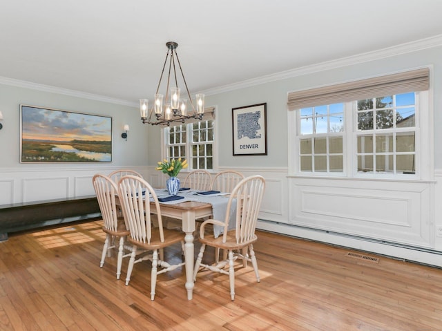 dining room featuring an inviting chandelier, ornamental molding, and light wood-type flooring